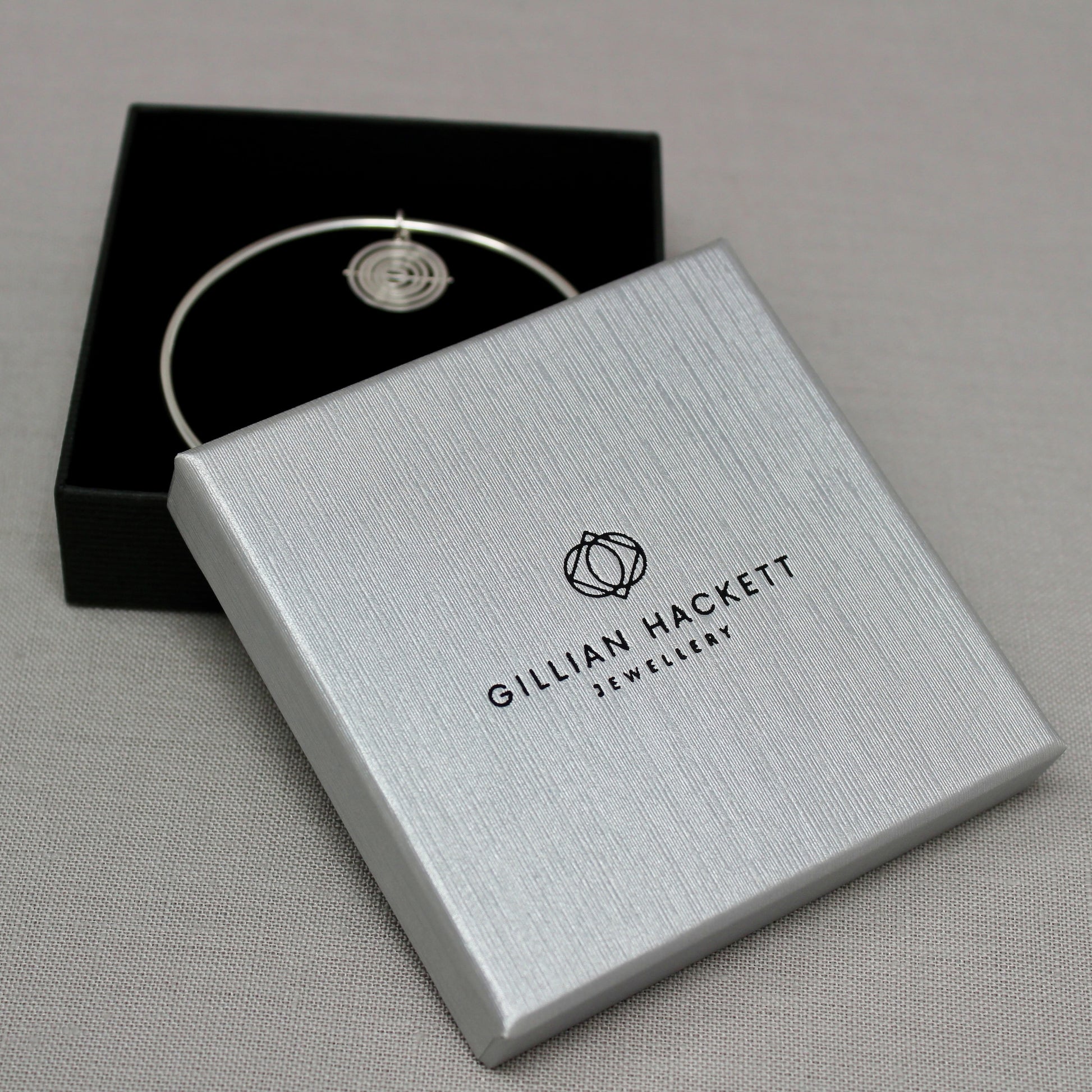 Hallmarked silver bangle & kinetic charm in Gillian Hackett Jewellery luxury black gift box with logo on grey textured lid