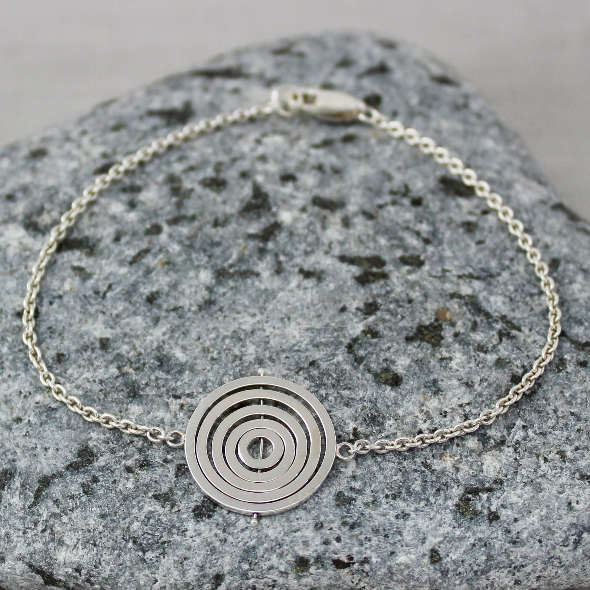 Handcrafted sterling silver kinetic bracelet with trace chain either side of 1.7cm concentric circle charm with lobster clasp