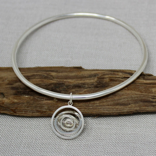 Hallmarked sterling silver handcrafted bangle with dangling kinetic charm made of 5 concentric rings pivoting on central pin