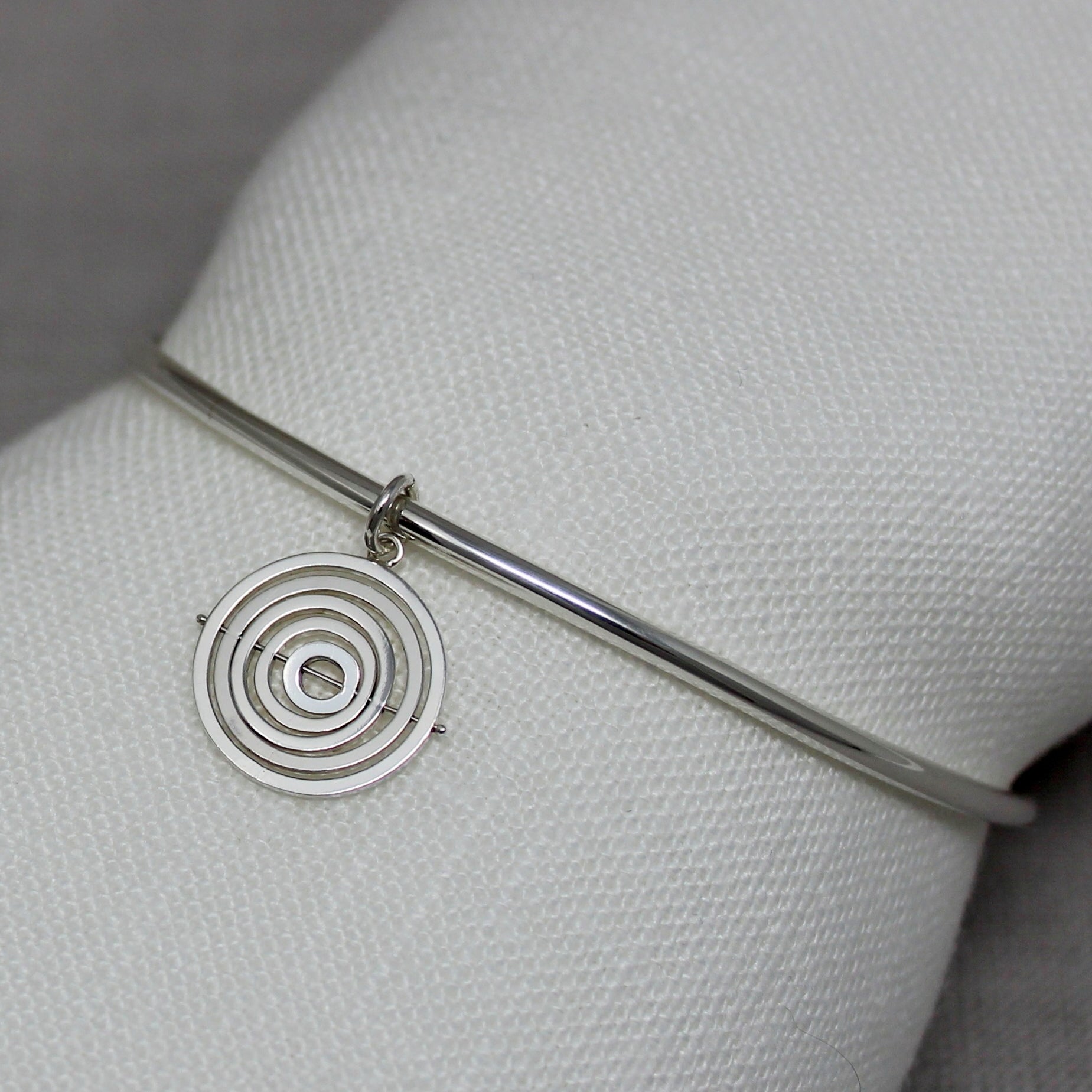 Hallmarked handmade recycled silver bangle with dangling 1.5cm kinetic charm of concentric square wire rings on central pin